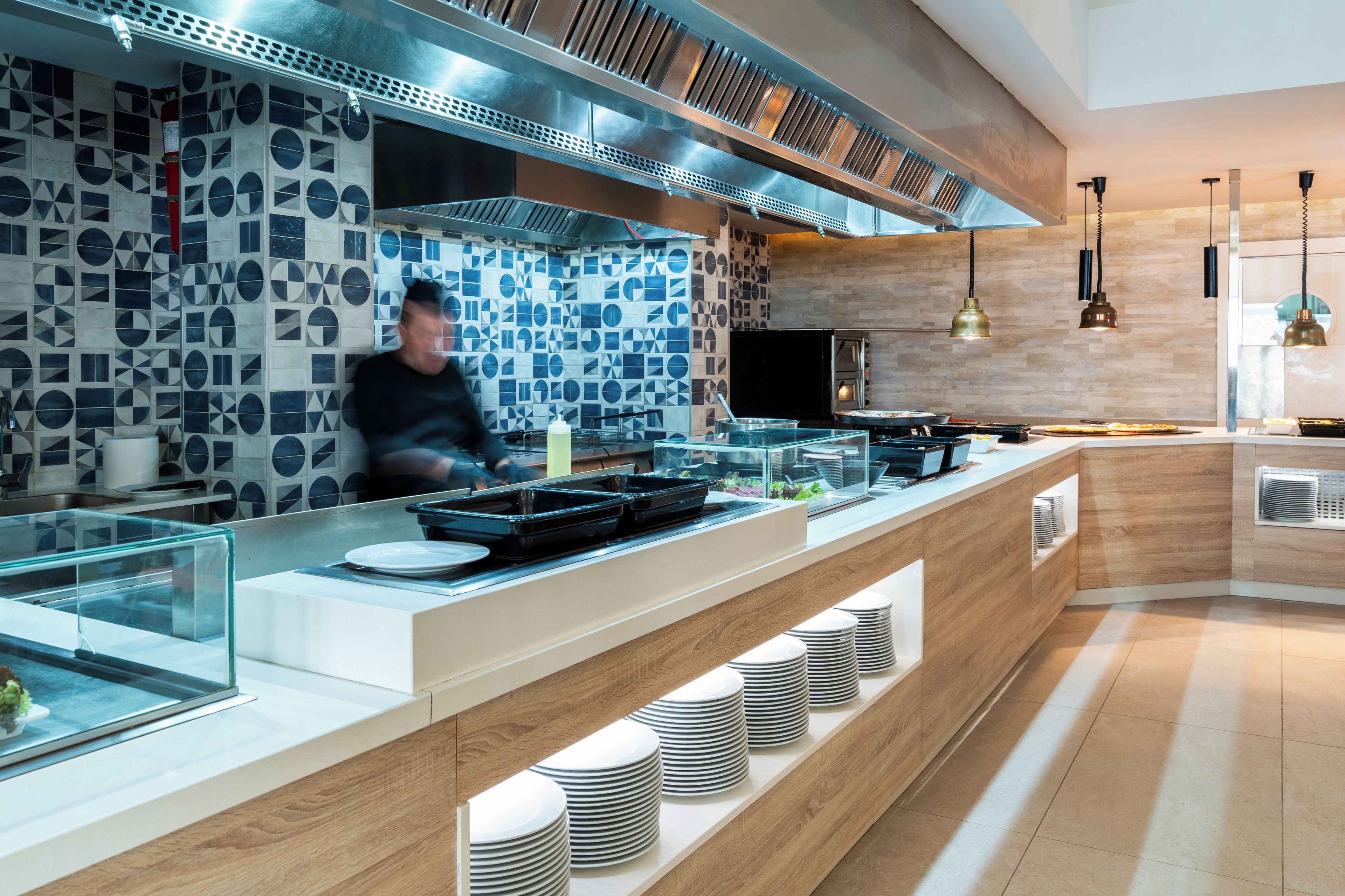 Een moderne keuken met een backsplash van geometrische tegels, roestvrijstalen apparatuur en een houten aanrecht.