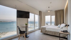 A hotel room with a bed, a desk, a chair, a TV, and a view of the sea. - Hotel Las Arenas (Palma de Mallorca)