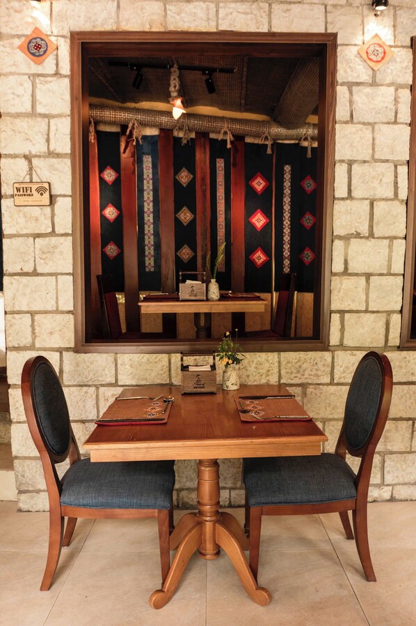 A wooden dining table with two chairs, a mirror above it, and a sign indicating WiFi availability. - Sapa Elegance Hotel (Sa Pa)