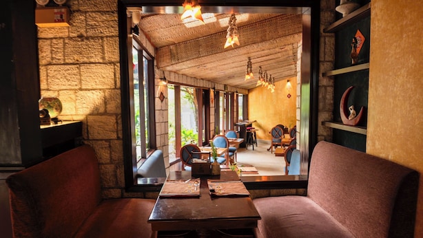 Un restaurante con paredes de piedra, muebles de madera y luces colgantes.