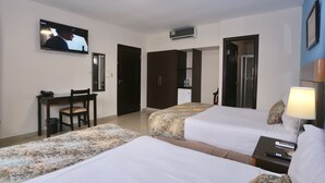 A hotel room with two beds, a desk, a TV, and a small kitchenette. - Metro Hotel Panama (Panama City)