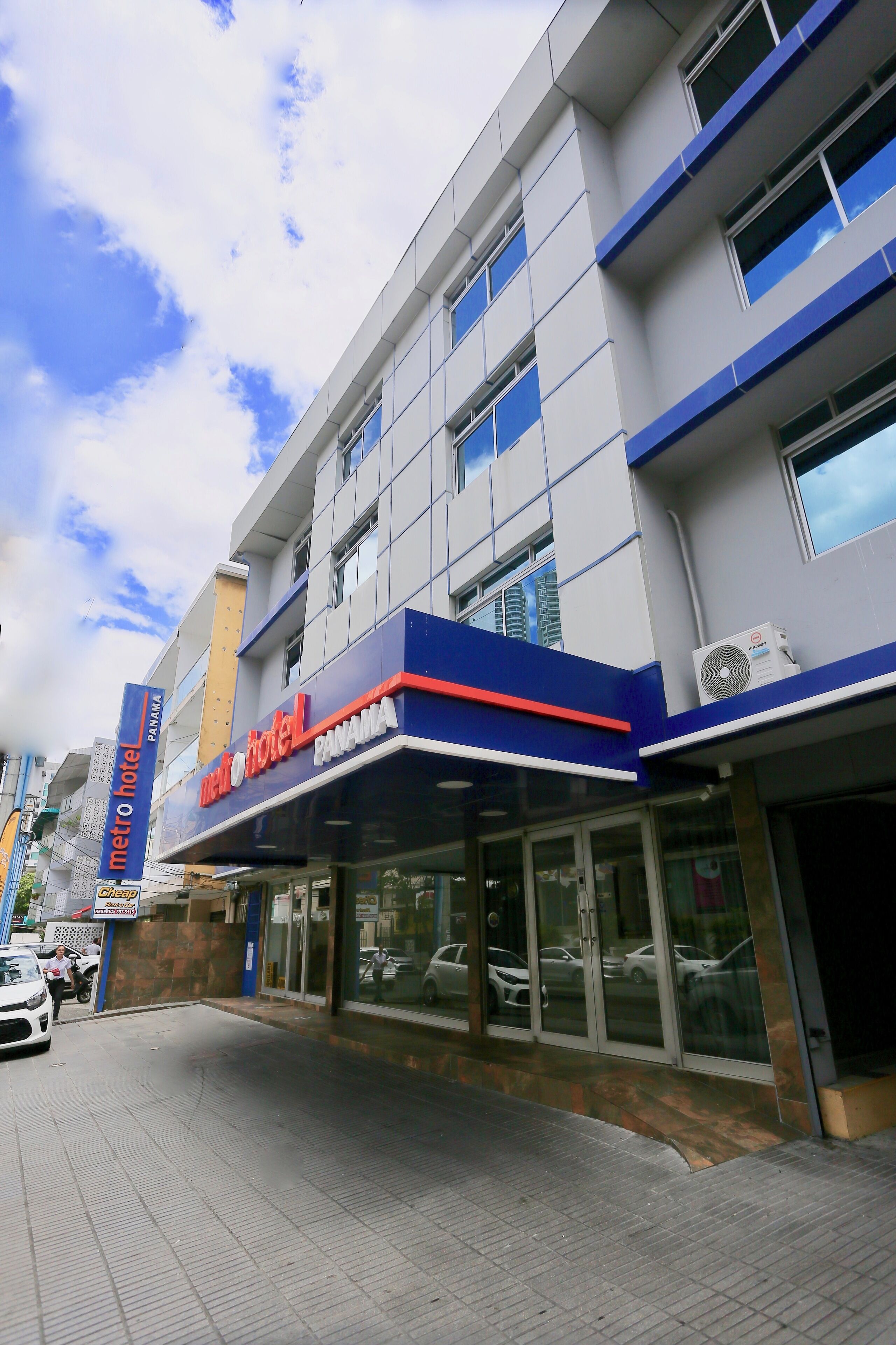 A hotel with a modern facade, large windows, and a visible air conditioning unit.