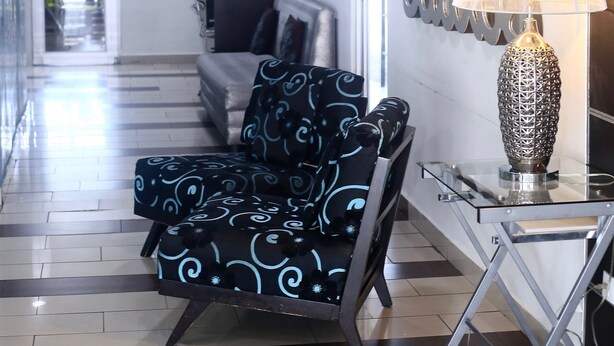 A modern living area with a sofa, a decorative wall, and a table with a lamp. - Metro Hotel Panama (Panama City)