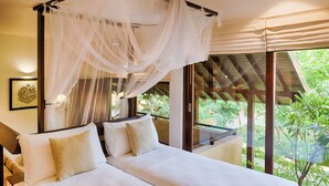 A bedroom with a canopy bed, a view of greenery outside, and a framed leaf artwork on the wall. - Jetwing Ayurveda Pavilions (Negombo)
