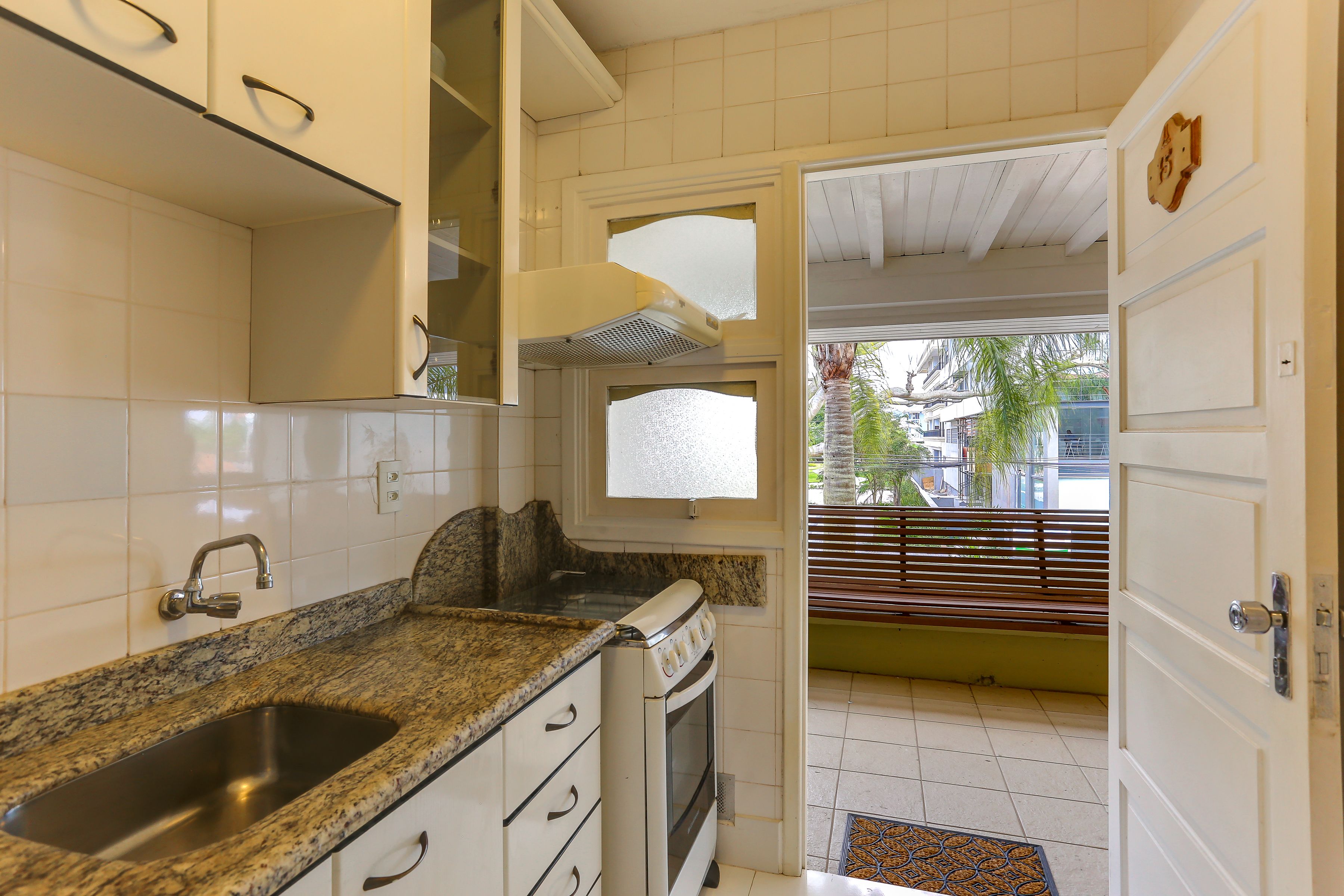 A kitchen with white cabinets, a granite countertop, a stainless steel sink, and a built-in oven.