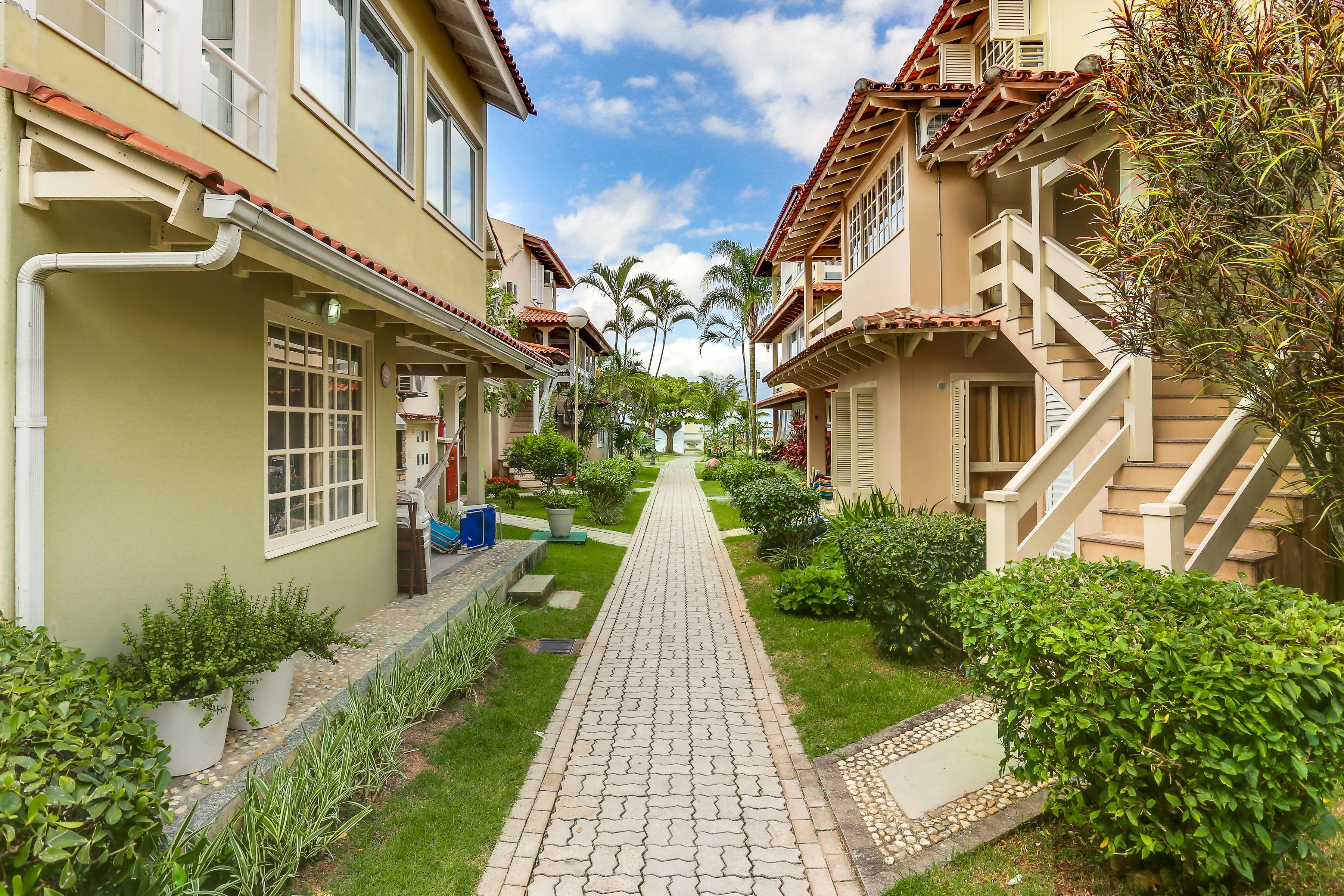 A narrow pathway flanked by buildings with balconies and a clear sky.