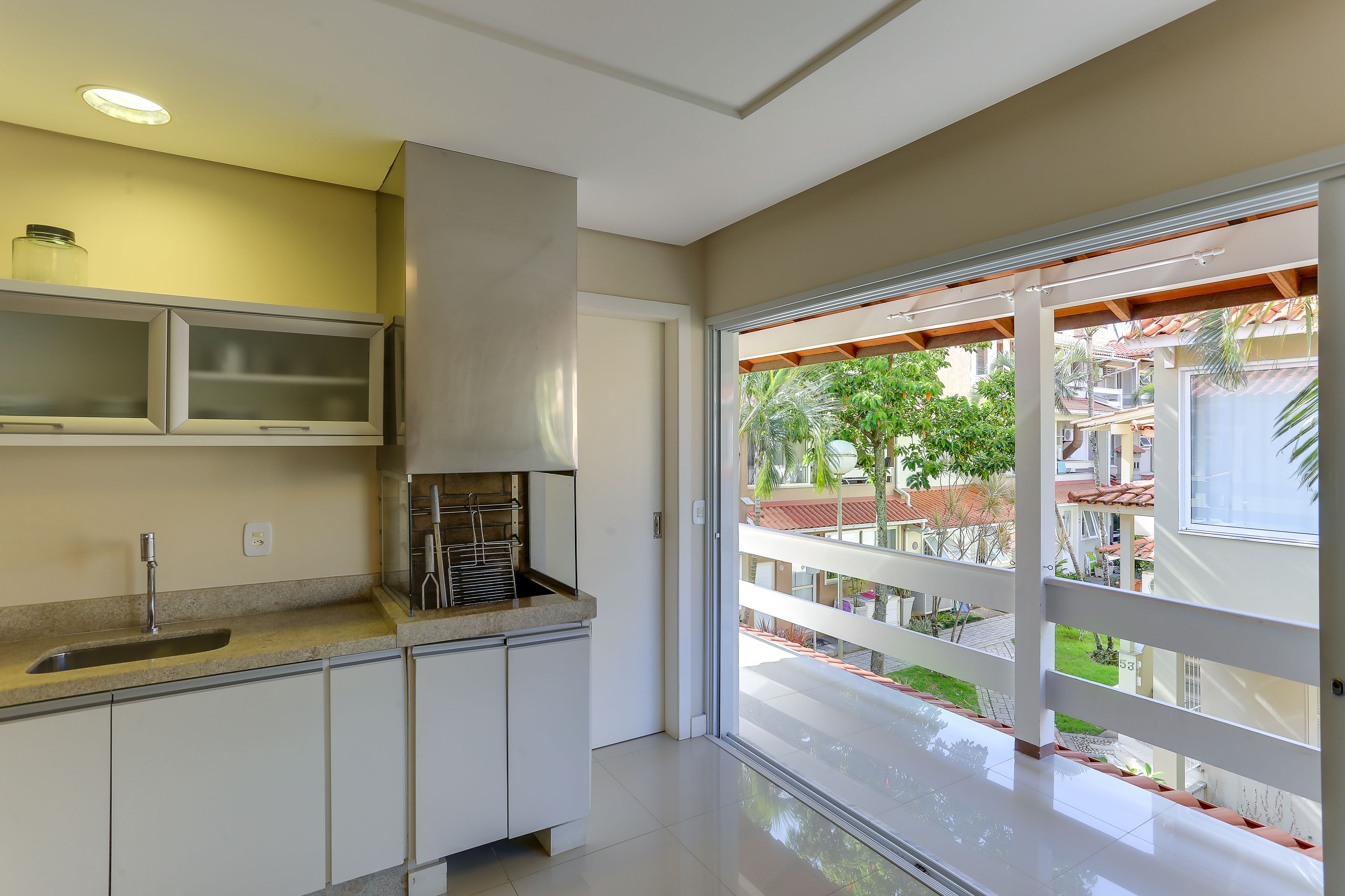 A modern kitchen with a built-in sink, cabinets, and a window overlooking a residential area.