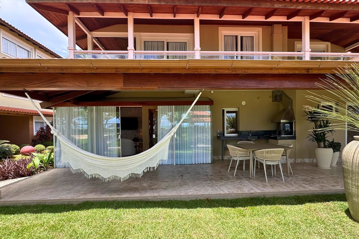 Ein zweistöckiges Gebäude mit Balkon, einer Hängematte und einer Terrasse mit Stühlen und einem Tisch.