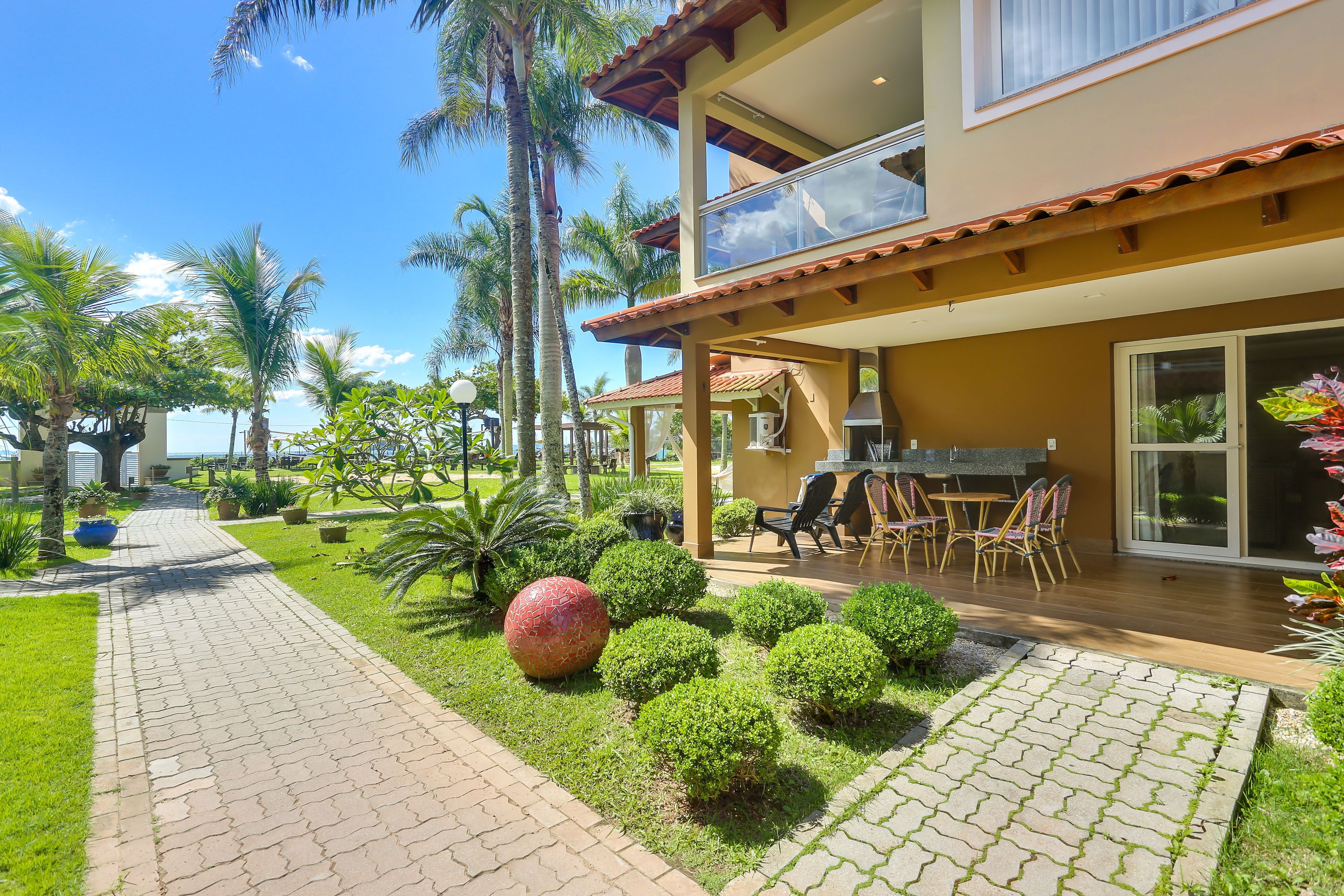 Una casa moderna de dos pisos con un patio, mobiliario exterior y jardines exuberantes.