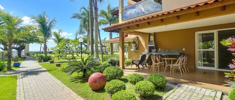 Una casa moderna de dos pisos con un patio, mobiliario exterior y jardines exuberantes.