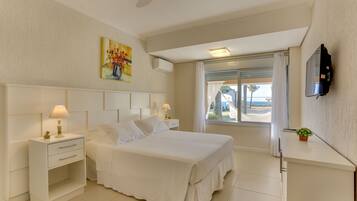 A hotel room with a bed, bedside tables, a TV, a window with curtains, and a painting on the wall.