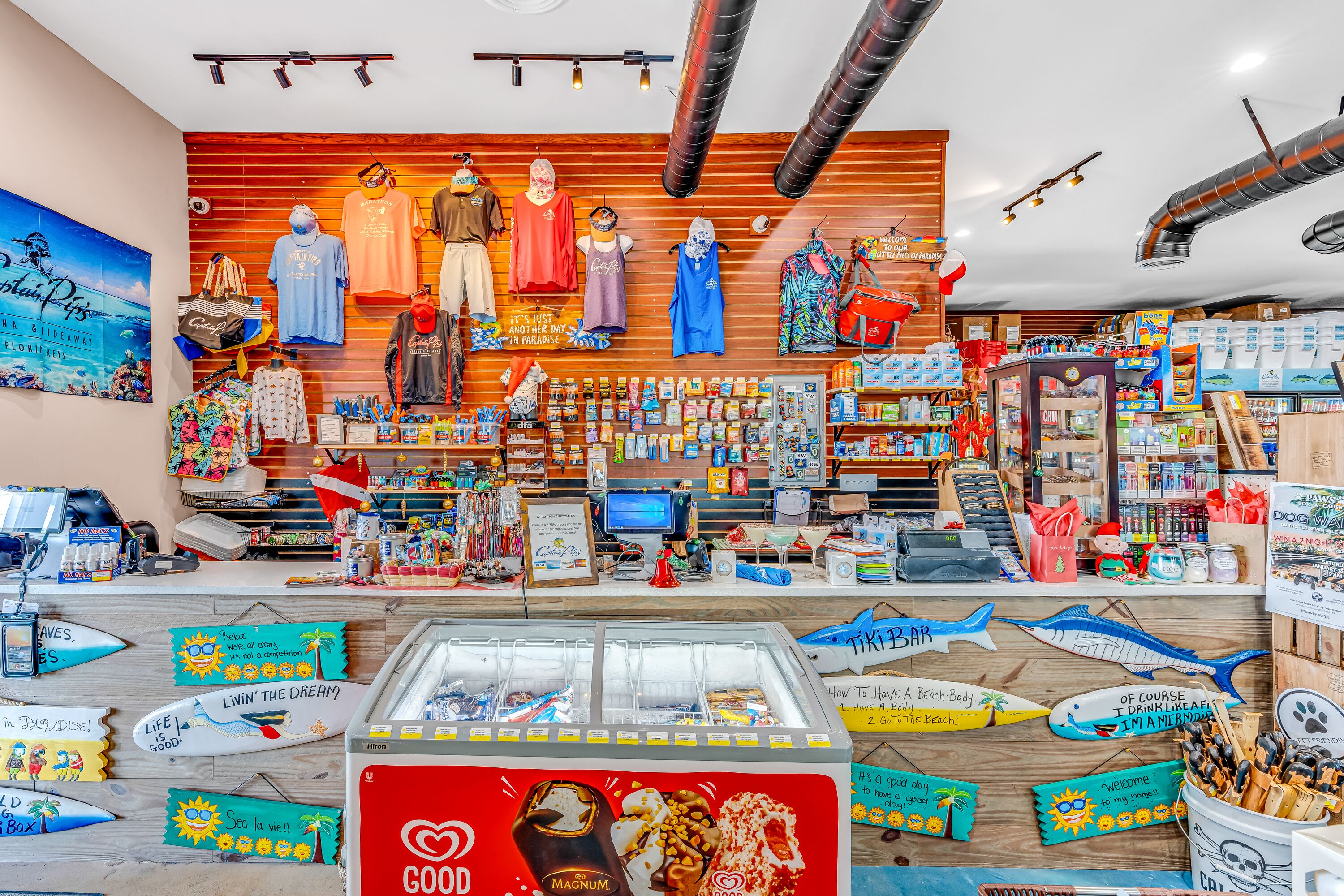 A beach-themed store with various souvenirs, a candy display, and a sign reading "It's just another day in paradise."