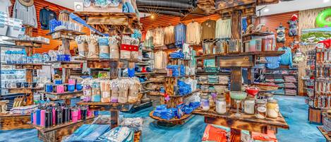 A store with various items on shelves and tables, including clothing, bags, and home decor.