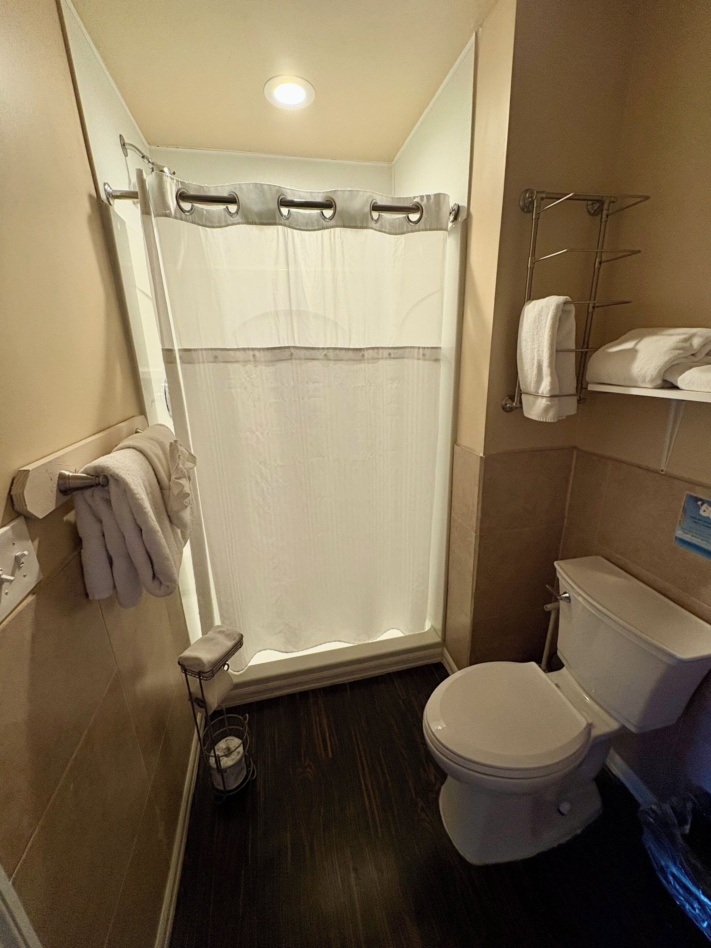 Une petite salle de bain avec un rideau de douche, des toilettes, un porte-serviettes et un lavabo.