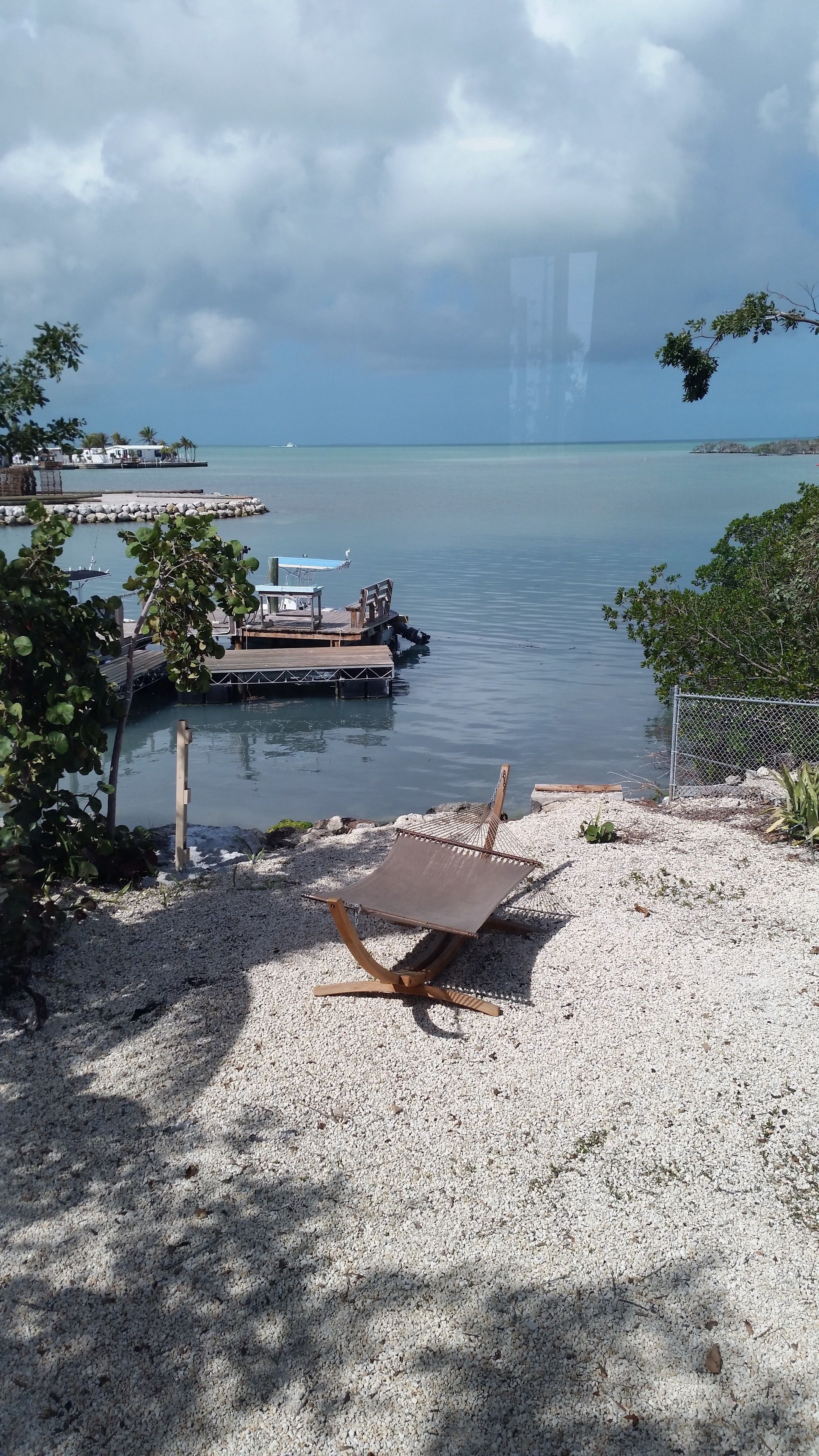 A beachside view with a wooden deck, a lounge chair, and a calm sea.