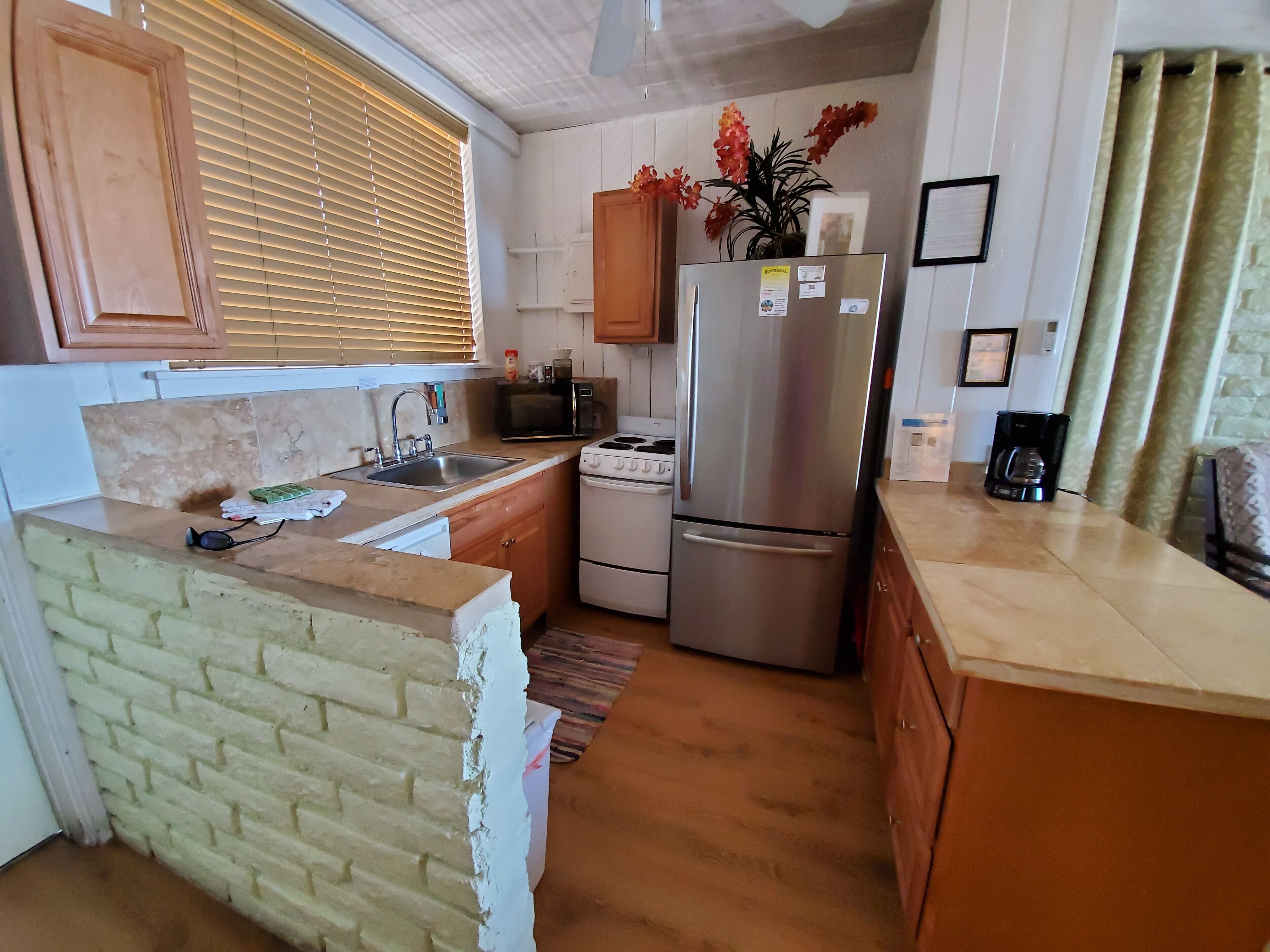 Una cocina compacta con lavamanos, estufa, microondas y refrigerador.