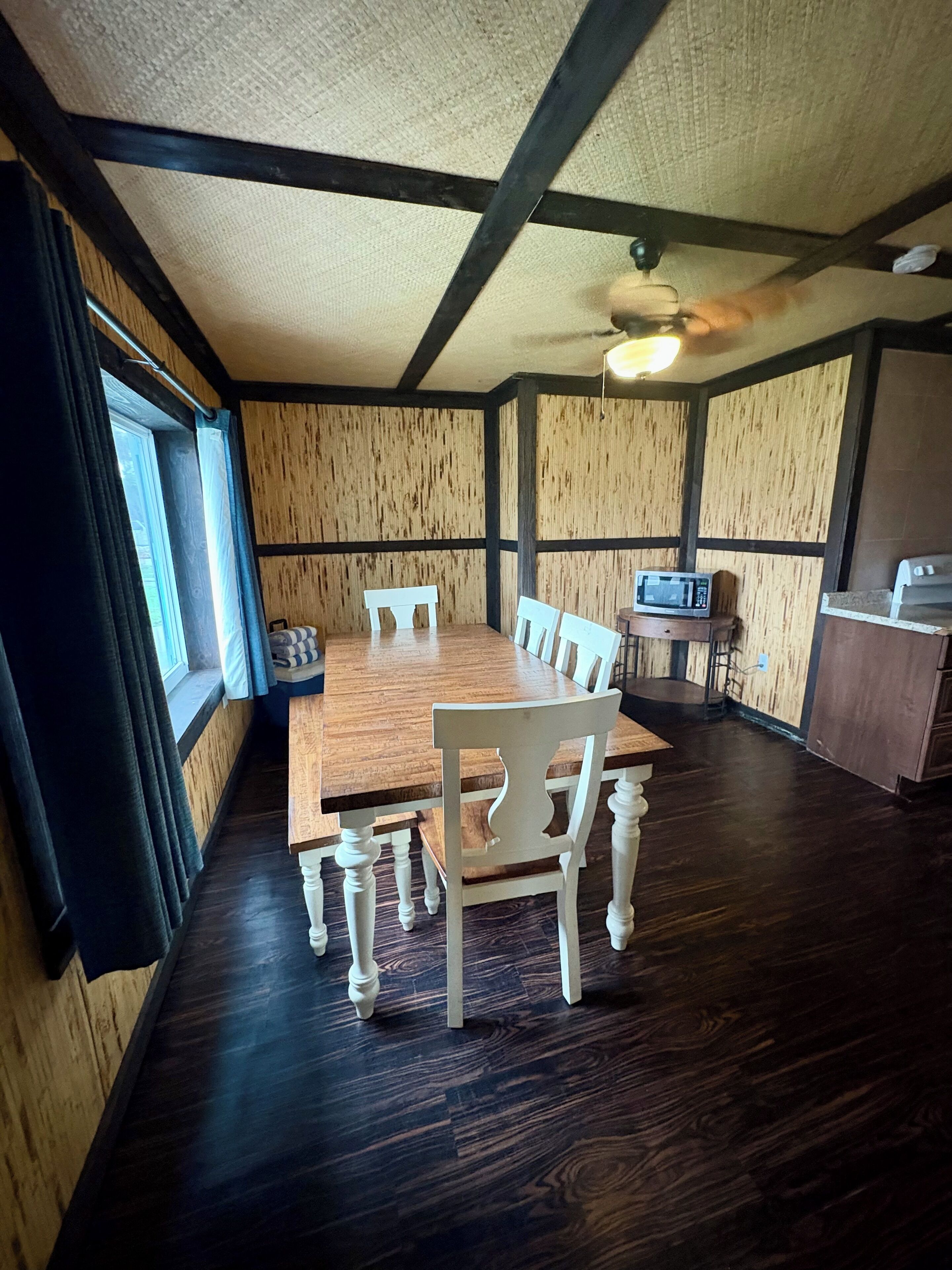 Ein Essbereich mit Holztisch und Stühlen, einer Mikrowelle und einer kleinen Küchenzeile.