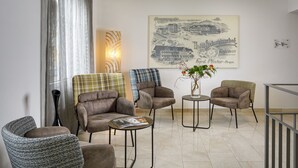 Un moderno vestíbulo de hotel con una gran obra de arte urbana enmarcada, asientos cómodos y una lámpara de pie decorativa.
