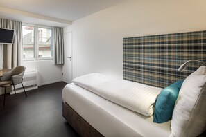Relax in a cozy space with a single bed, desk, and flat-screen TV.