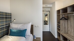Un dormitorio con cama, mesita de noche y armario de madera con barra para colgar ropa.