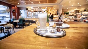Una mesa con un vaso de cerveza, un vaso de agua y un muffin.