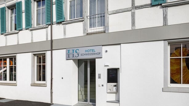 Entrada de un hotel con un letrero que dice 'HOTEL SCHWEIZERHOF'.