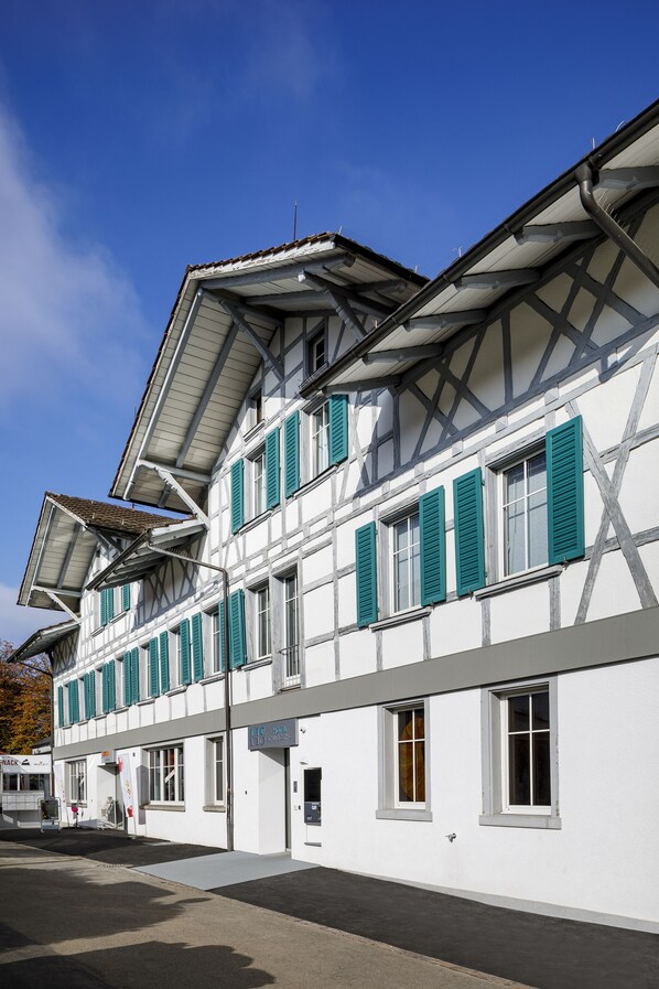 A white building with green shutters and a sloped roof. - Hotel Schweizerhof Wetzikon (Wetzikon)