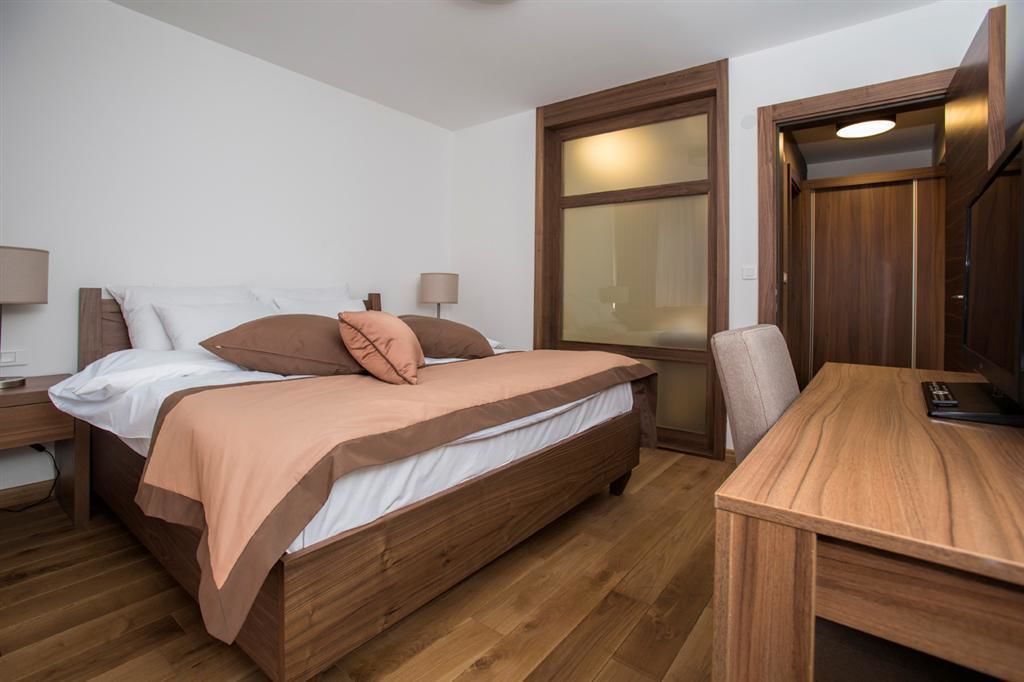A room with a wooden bed, a desk, and a window.
