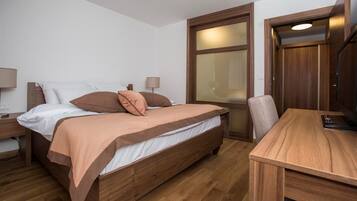 A room with a wooden bed, a desk, and a window.