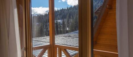 Un balcon en bois offrant une vue sur des montagnes enneigées et un ciel dégagé.