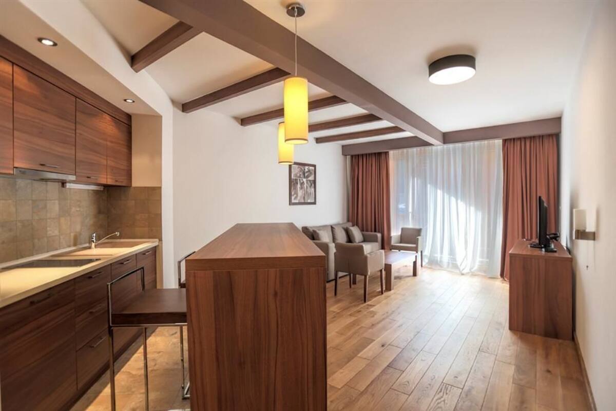 A modern kitchen with wooden cabinets, a central island, and pendant lighting.
