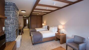 A hotel room with two beds, a stone accent wall, wooden beams, a television, a desk, and a chair.