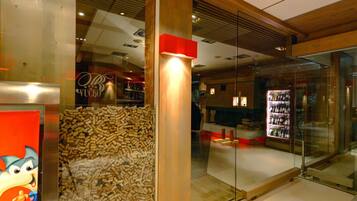 Een modern interieur met houten balken, een glazen scheidingswand en een presentatie van wijnflessen.