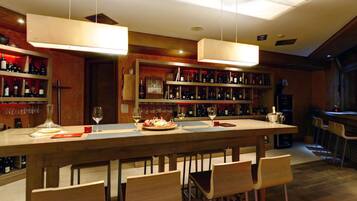 A bar area with a long counter, multiple wine bottles, and bar stools.