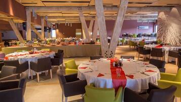 Un restaurant avec des tables rondes, des chaises et un plafond haut avec des poutres apparentes.
