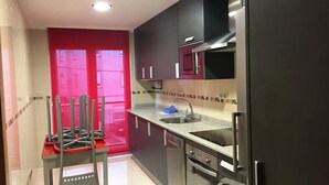 Une cuisine moderne dotée d’appareils électroménagers en acier inoxydable, d’une porte rouge et d’un dosseret carrelé.