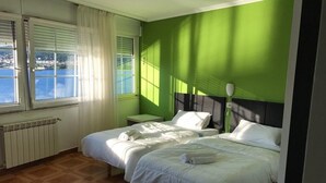 Une chambre avec deux lits, une fenêtre donnant sur la mer et un radiateur.