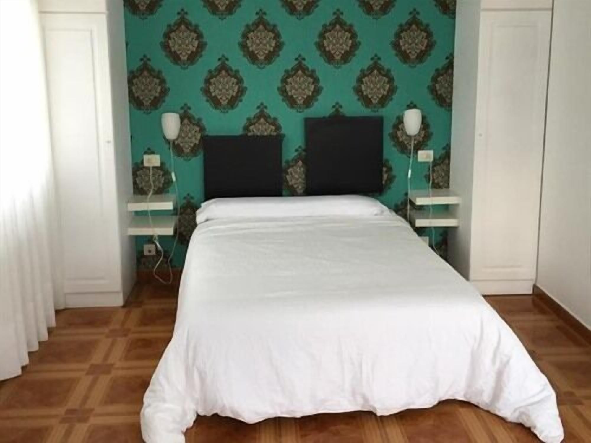 A bedroom with a bed, two bedside tables, and a patterned wall.
