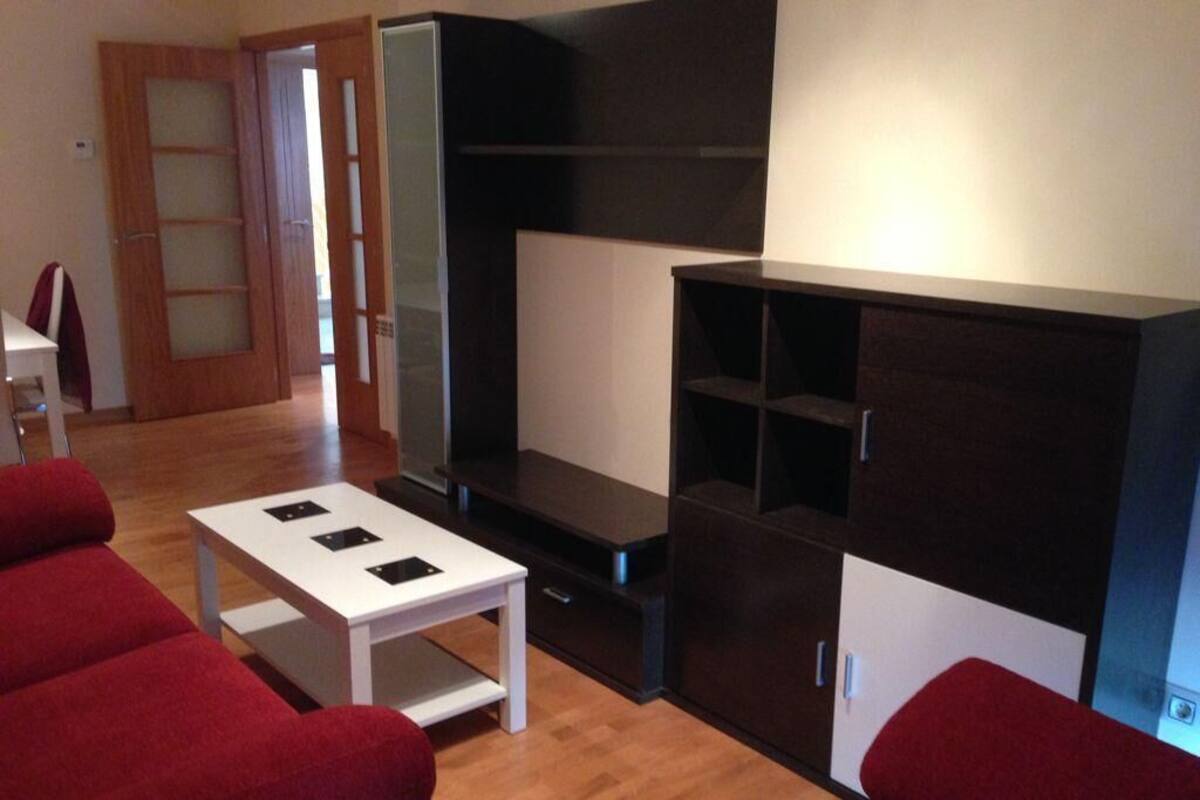 Ein modernes Wohnzimmer mit einer Sofagarnitur, einem Couchtisch und einer TV-Konsole.
