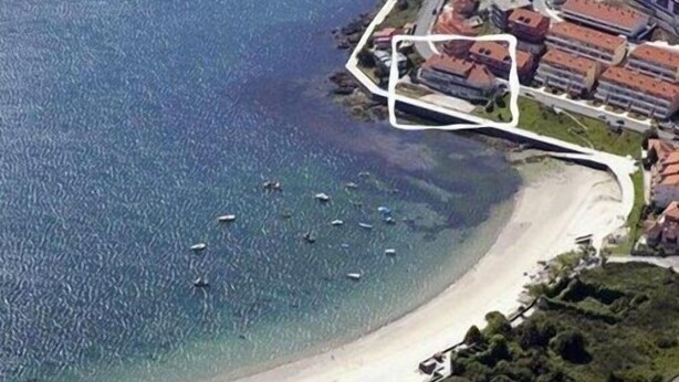 Une vue aérienne d’une zone côtière avec une plage, des bateaux et des bâtiments.
