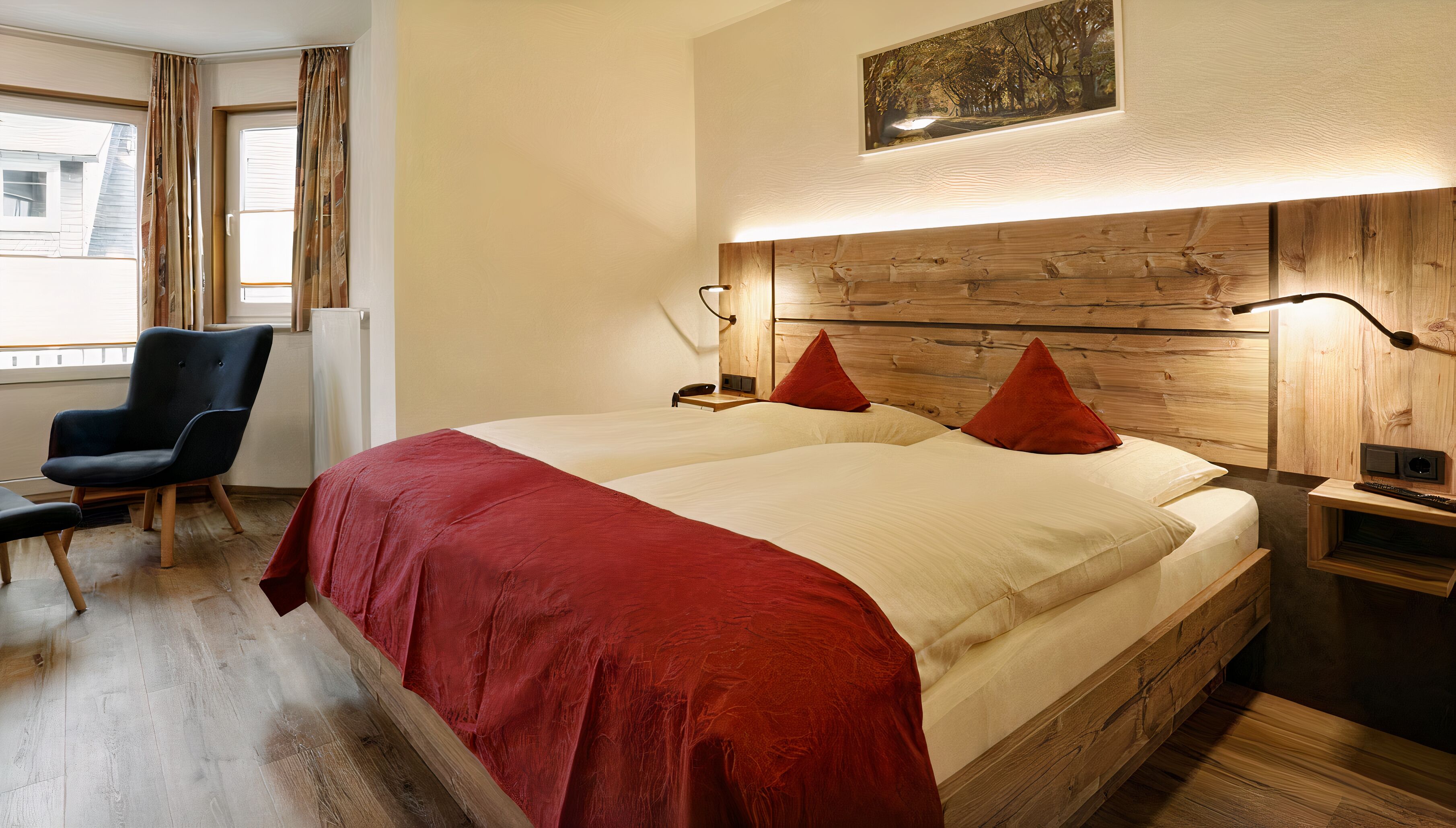 Una cama doble con almohadas rojas, un cabecero de madera y una mesita de noche con lámpara.