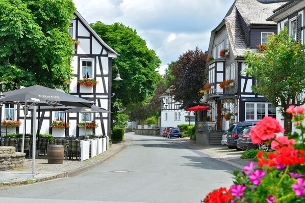 A traditional half-timbered building with a pub on the ground floor, outdoor seating, and a street view. - Landhotel Albers (Schmallenberg)