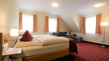 Una habitación de hotel con una cama grande, un escritorio, un sofá y una lámpara de pie.