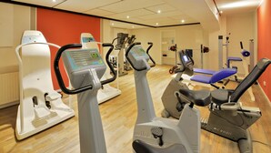 A gym with various exercise machines, including ellipticals and a rowing machine. - Landhotel Albers (Schmallenberg)