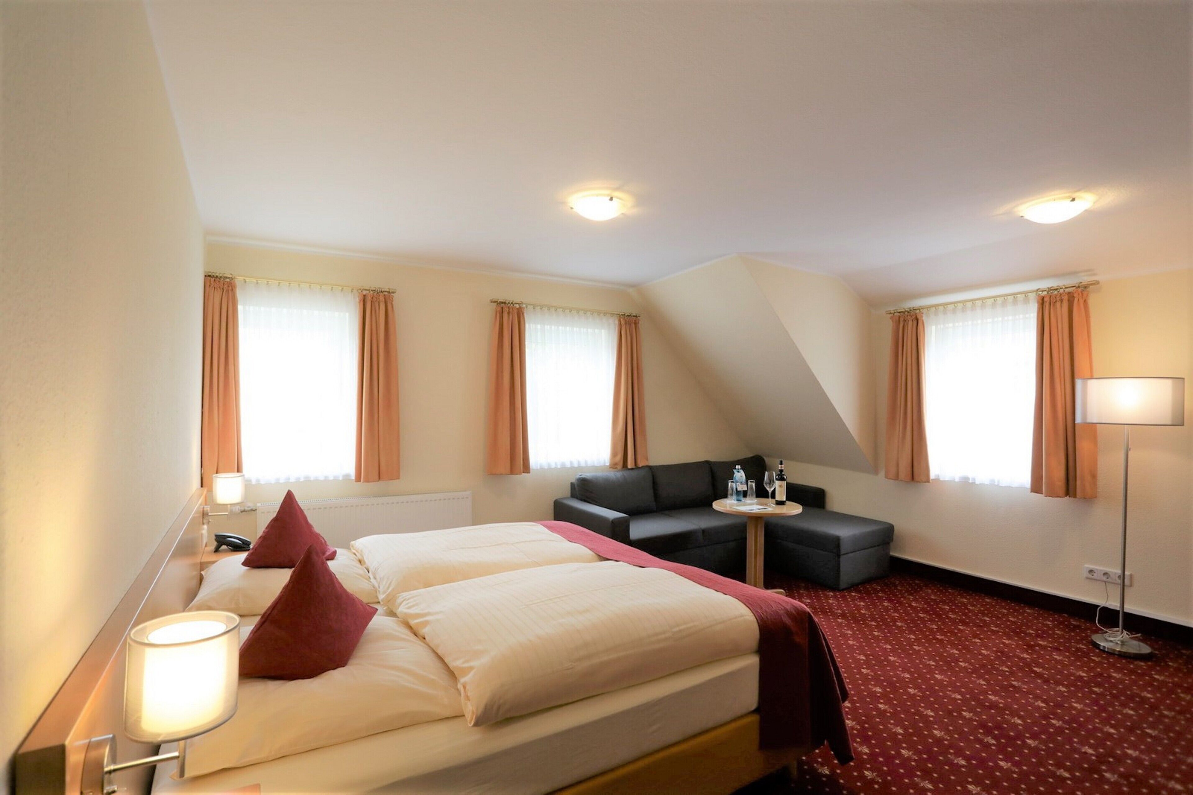 A hotel room with two beds, a sofa, a small table, and a lamp.