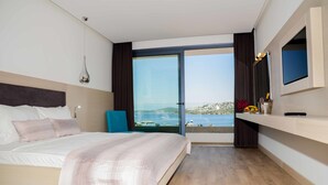 A modern hotel room with a large bed, a television, a view of the sea, and a balcony with a cityscape in the background. - Most City Premium apartments (Dnipro)