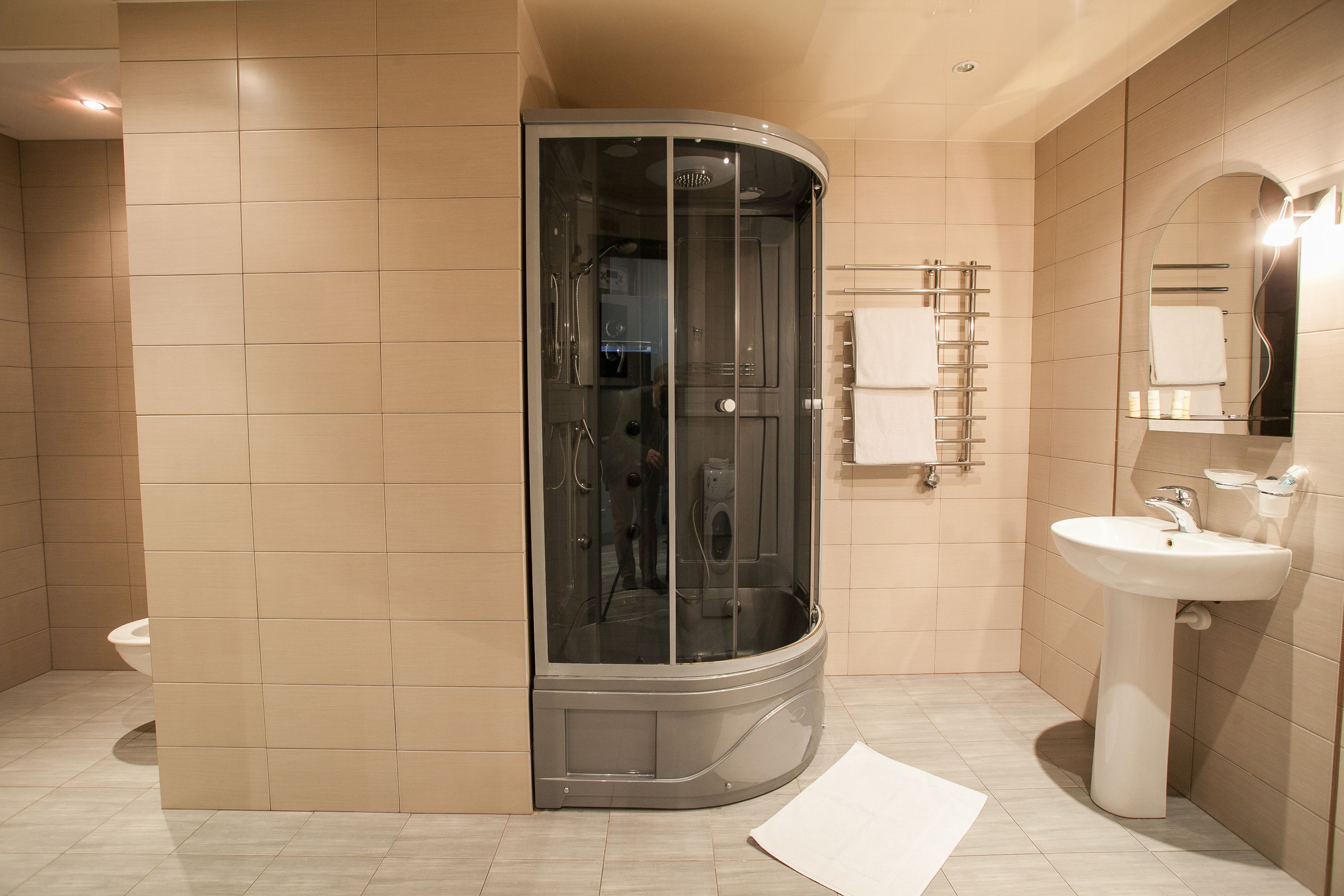 Un baño moderno con cabina de ducha de vidrio, un lavabo blanco y un perchero para toallas.