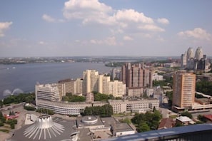 A high-rise hotel with multiple floors, a central courtyard, and a view of a river and city skyline. - Most City Premium apartments (Dnipro)