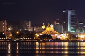 A nighttime cityscape with a prominent golden-domed building reflecting on the water. - Most City Premium apartments (Dnipro)