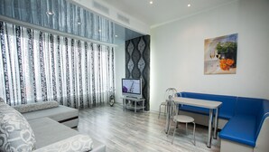 A modern living room with a grey sofa, a blue couch, a small table, and a TV on a stand. - Most City Premium apartments (Dnipro)